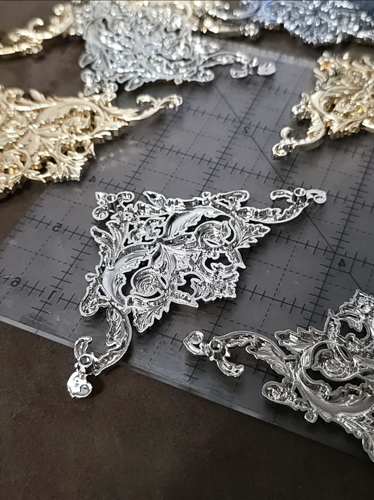 Decorative silver lace pieces on a cutting mat