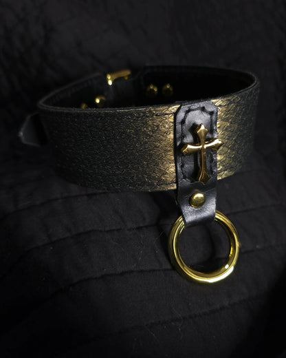 Black leather choker with gold cross and ring on a black background