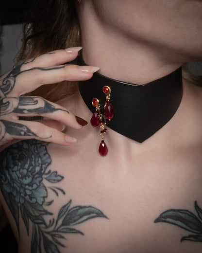 Person wearing a black choker with red teardrop-shaped beads, close-up on neck and chest.