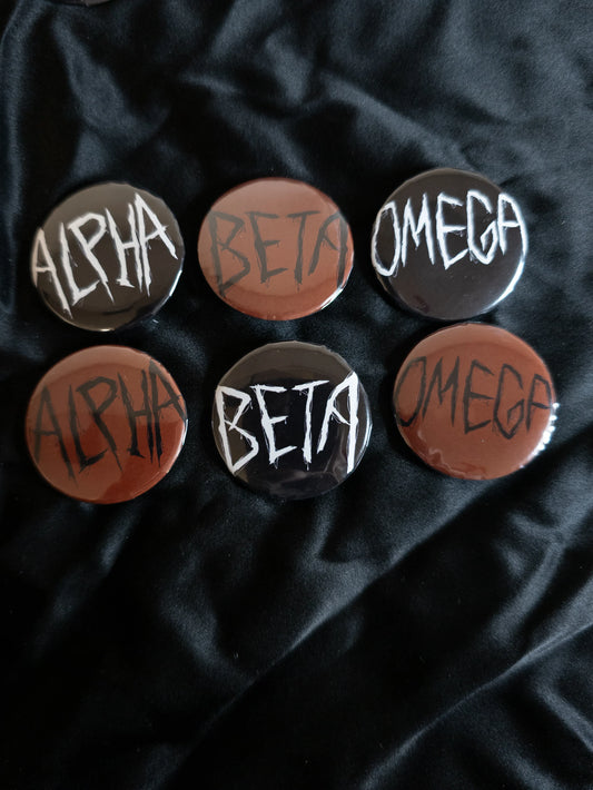 Set of buttons with 'Alpha', 'Beta', and 'Omega' text on a dark fabric background