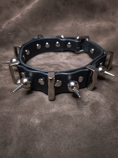 Black leather collar with metal spikes on a brown background