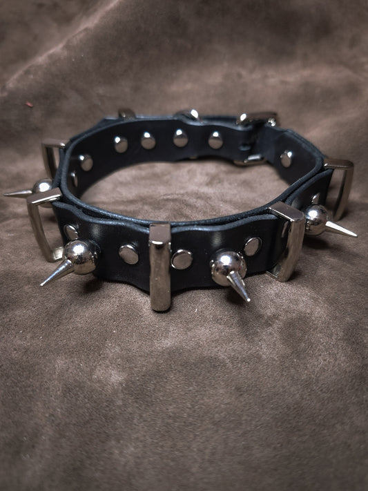 Black leather collar with metal spikes on a brown background