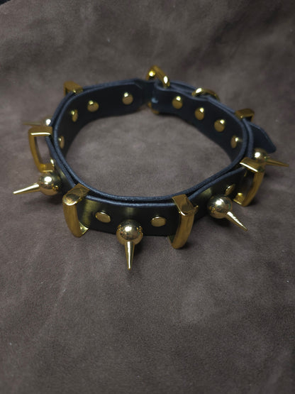 Black leather collar with gold spikes on a gray background