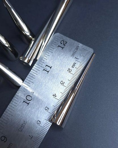Metal spike with a ruler for scale on a dark background