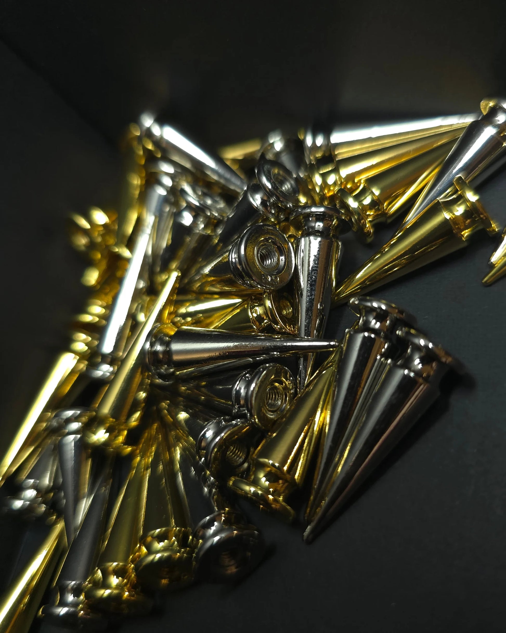 Close-up of gold and silver metal spikes on a dark background