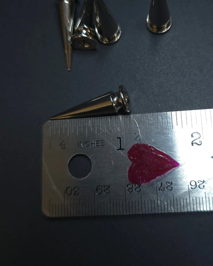 Metallic cone-shaped spike on a ruler with measurements