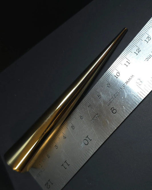 Gold spike next to a metal ruler on a black background