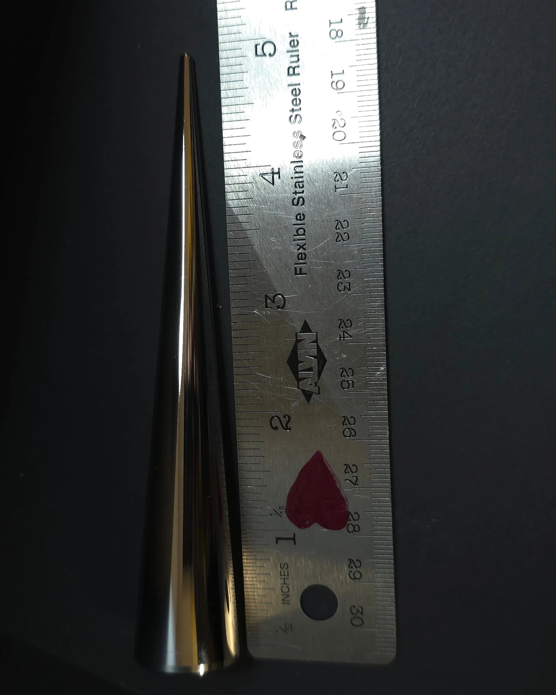 Silver spike next to ruler for scale
