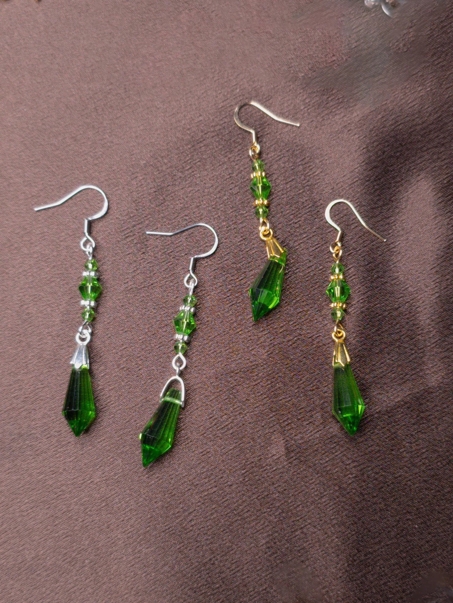 Green glass bead earrings in gold and silver on brown background
