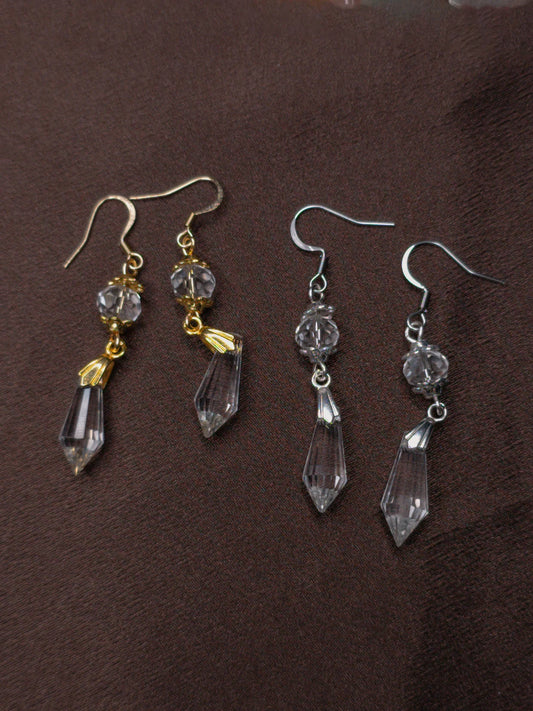 Pair of crystal drop earrings on a brown background