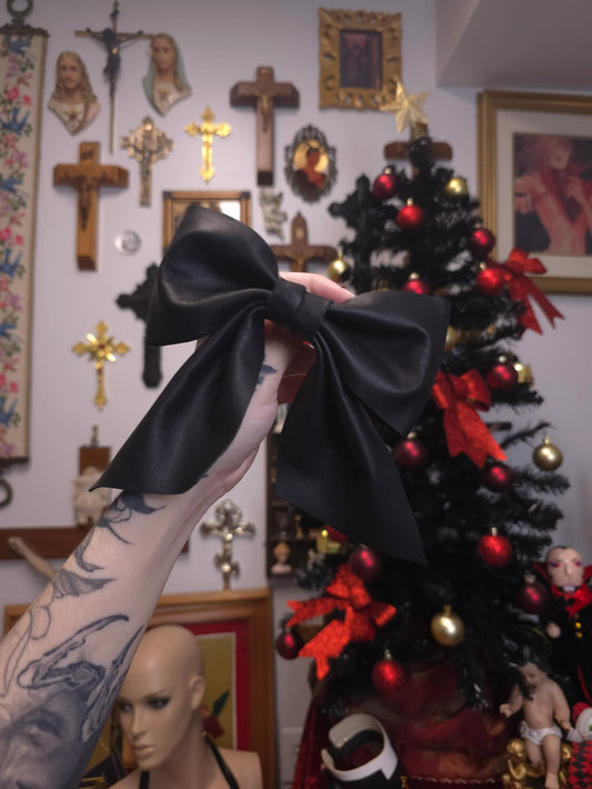 Hand holding a black leather bow against gallery wall