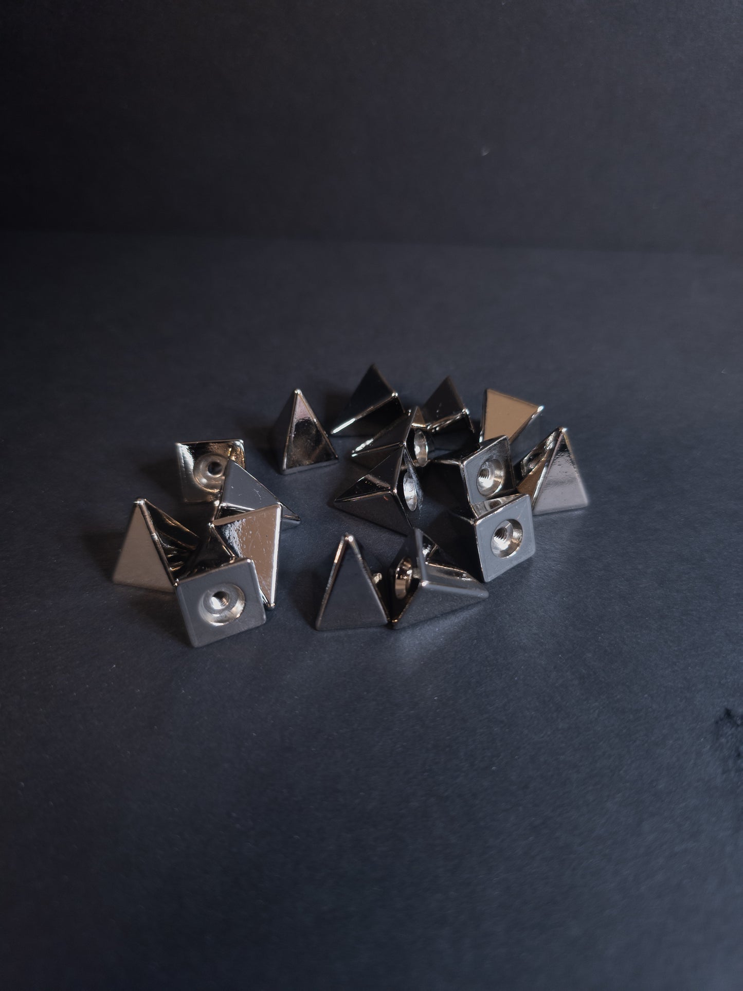 Set of metallic pyramid-shaped studs on a dark background