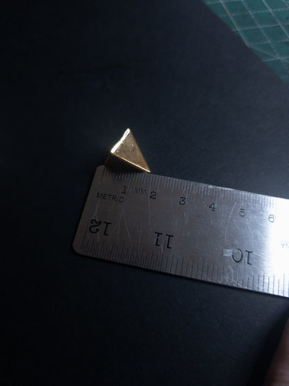 Metal ruler with a pyramid spike on a dark surface