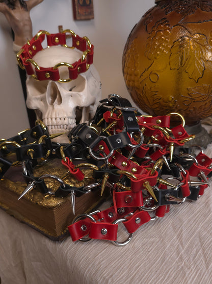 Red and black leather dog collars with metal clasps on a textured surface.