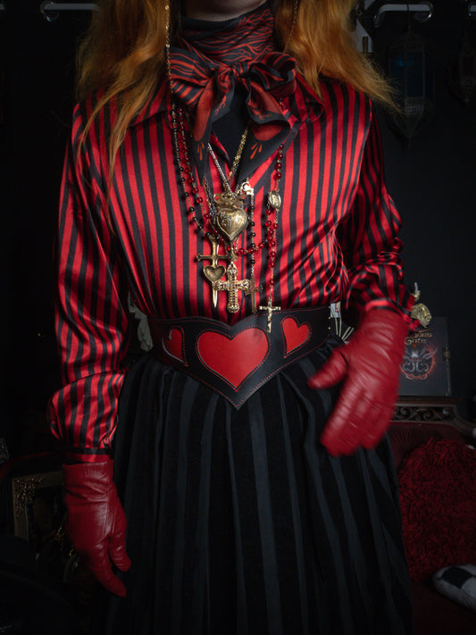 Person wearing a red and black striped shirt with heart details, red gloves, and a dark skirt.