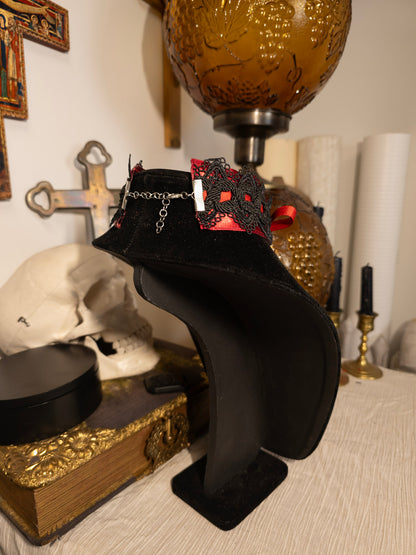 black necklace display with red ribbon choker against gothic decor