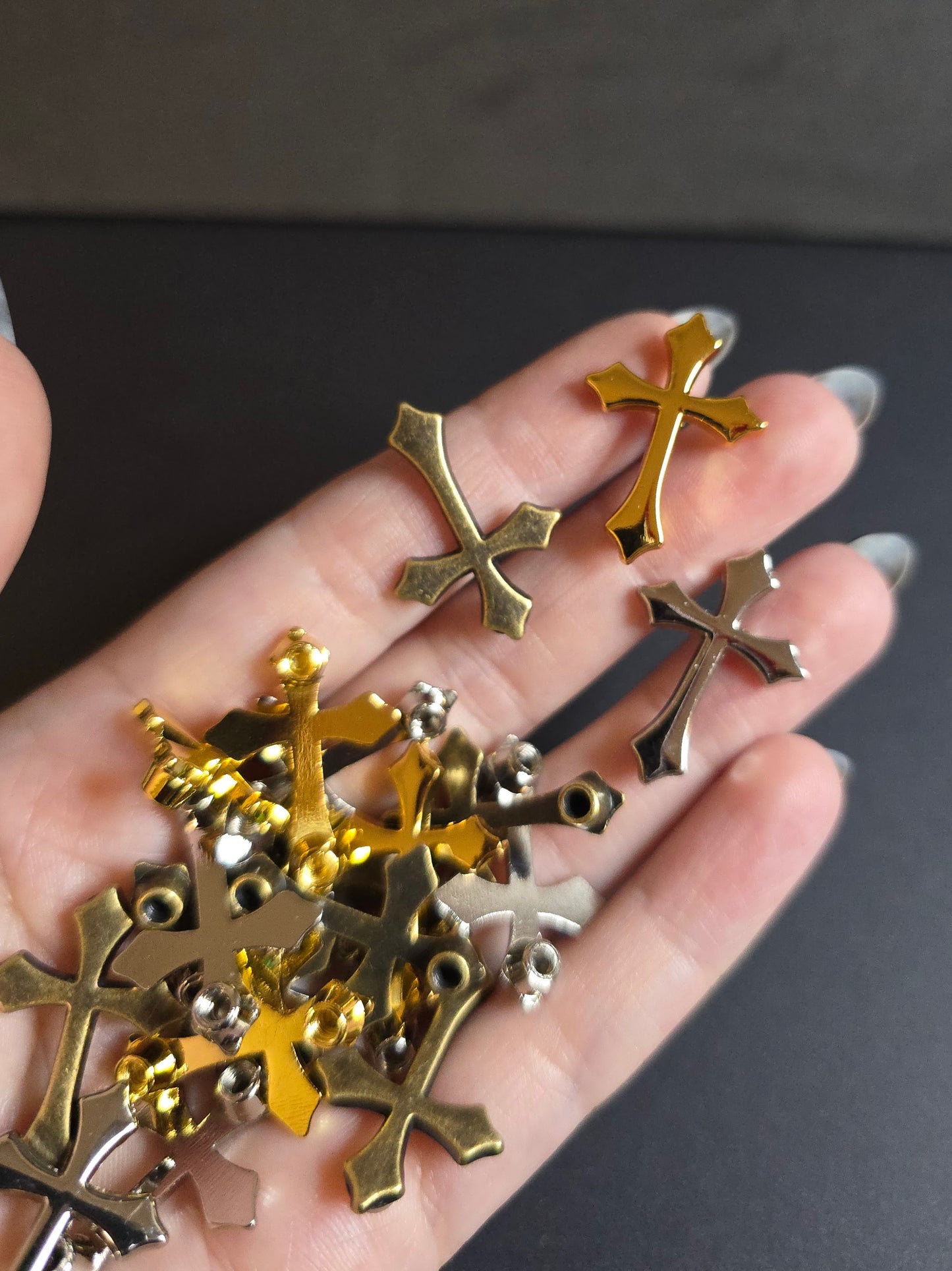 hand holding metal crosses on black background 