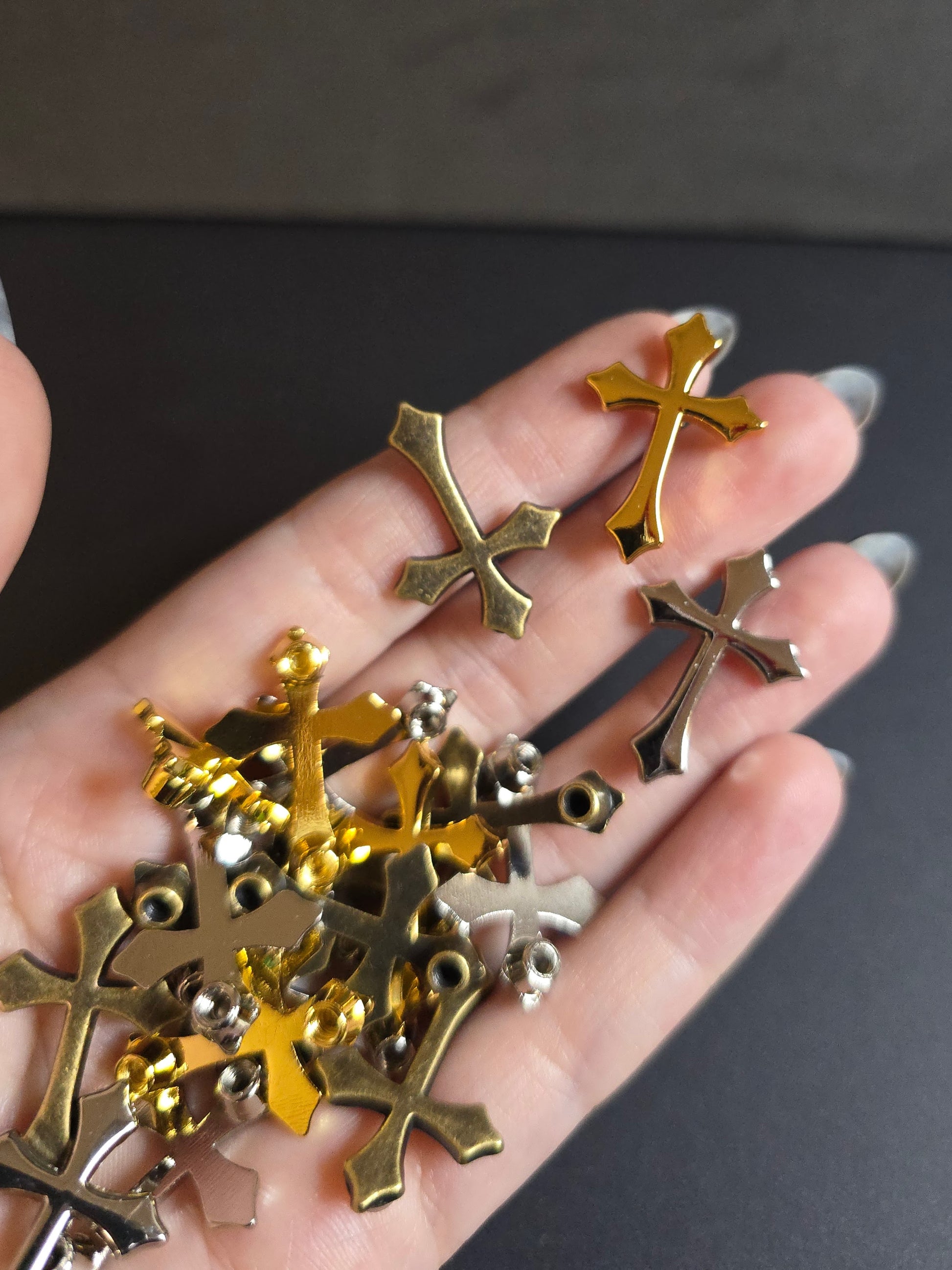 hand holding metal crosses on black background 