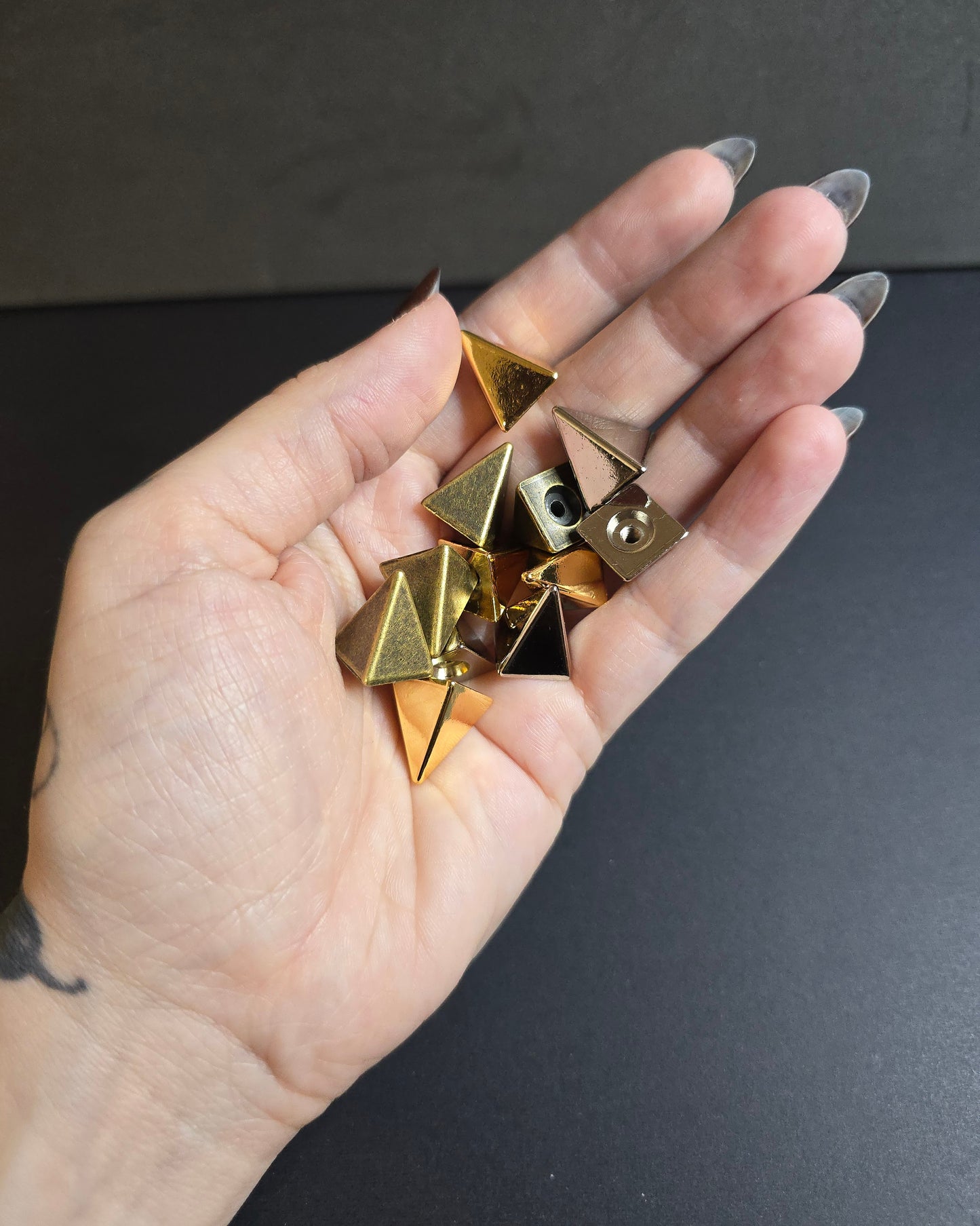 hand holding pyramid spikes on black background