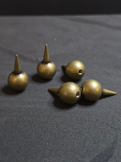 Set of bronze-colored metal spikes on a dark gray background
