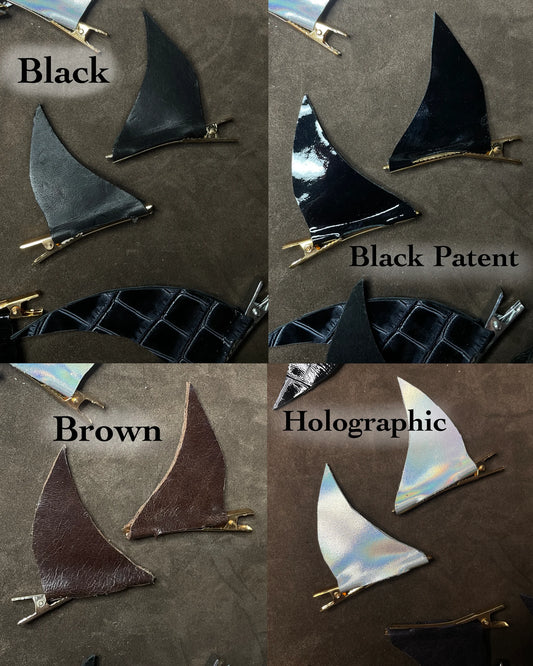 Four different colored horn-shaped hair clips on a brown background.