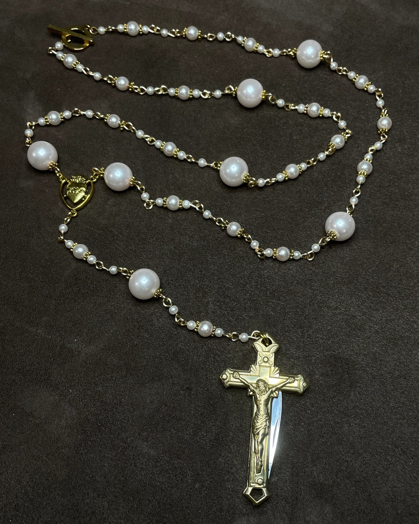 Pearl rosary with a gold cross pendant on a dark background