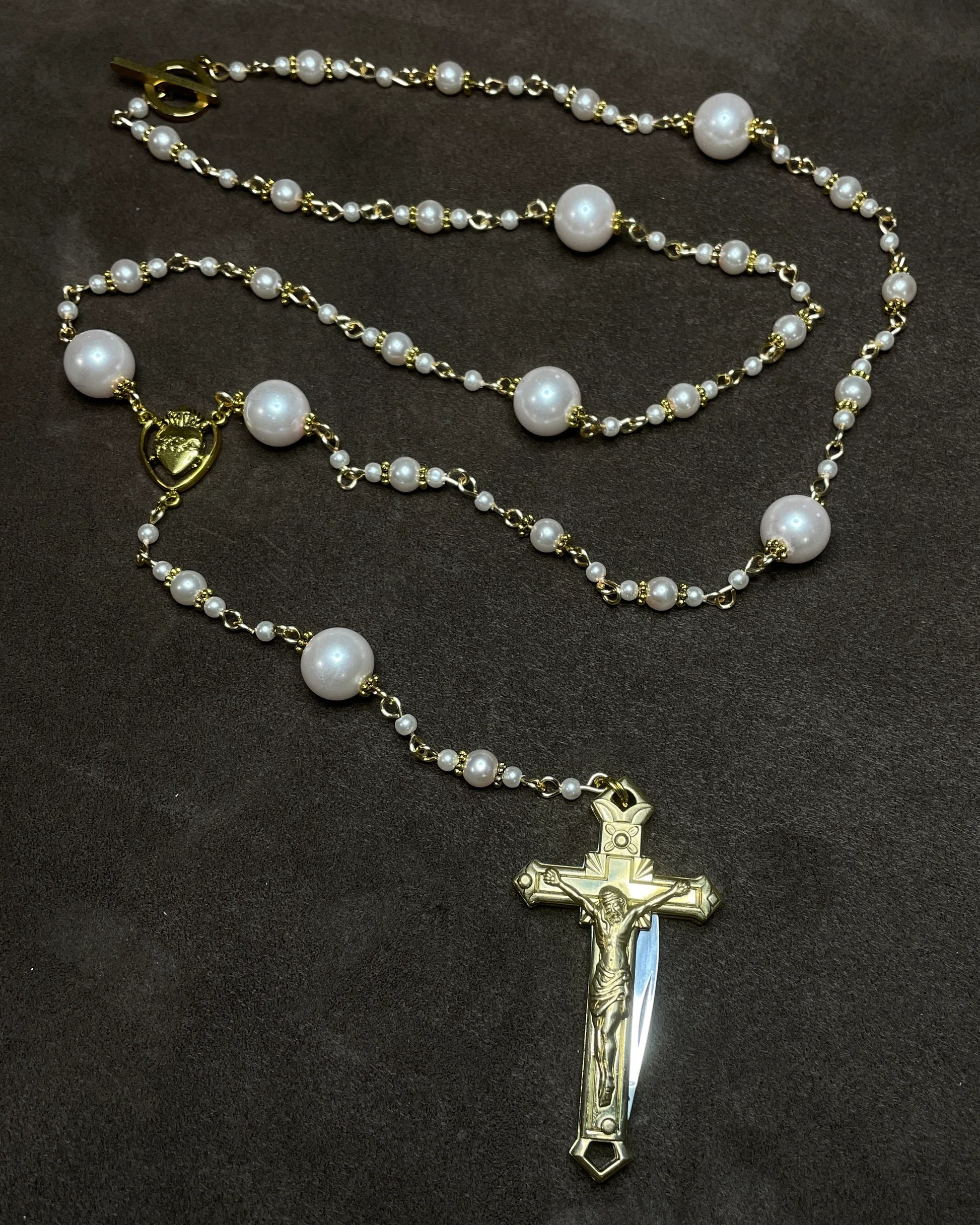 Pearl rosary with a gold cross pendant on a dark background