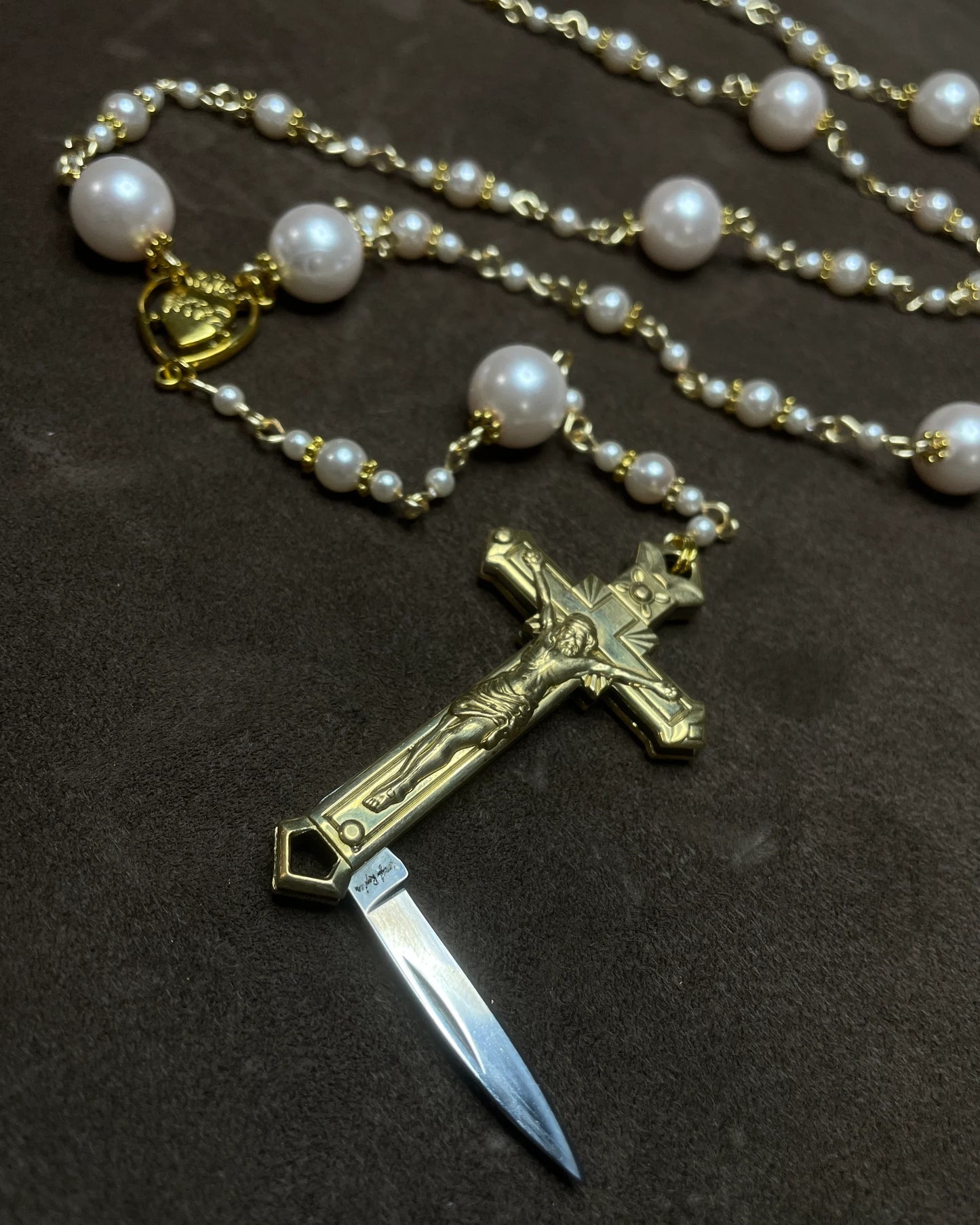 Rosary with a cross and knife on a dark background