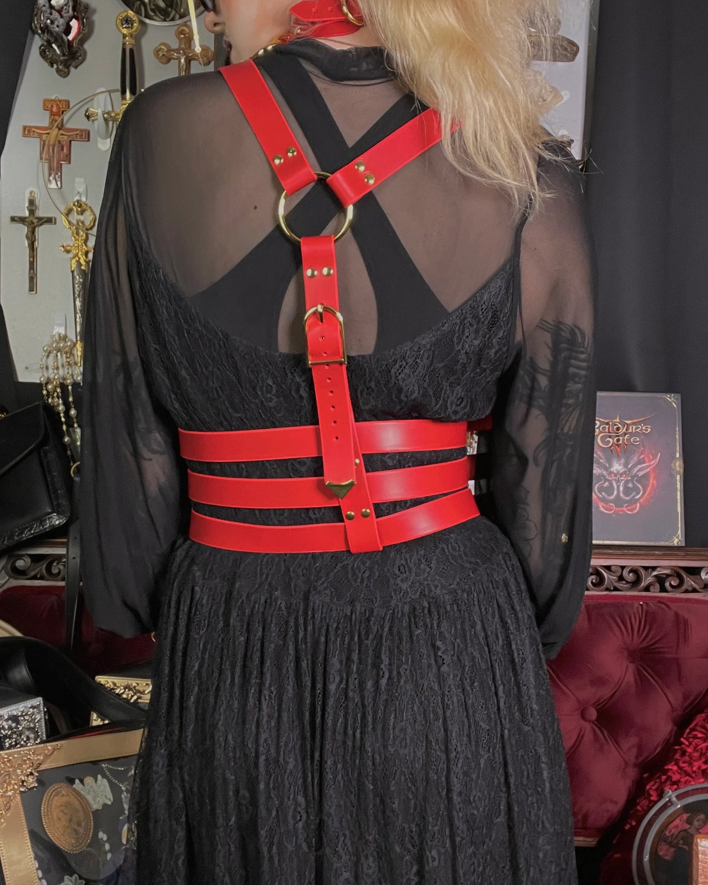 Person wearing a black dress with a red harness in a decorative setting