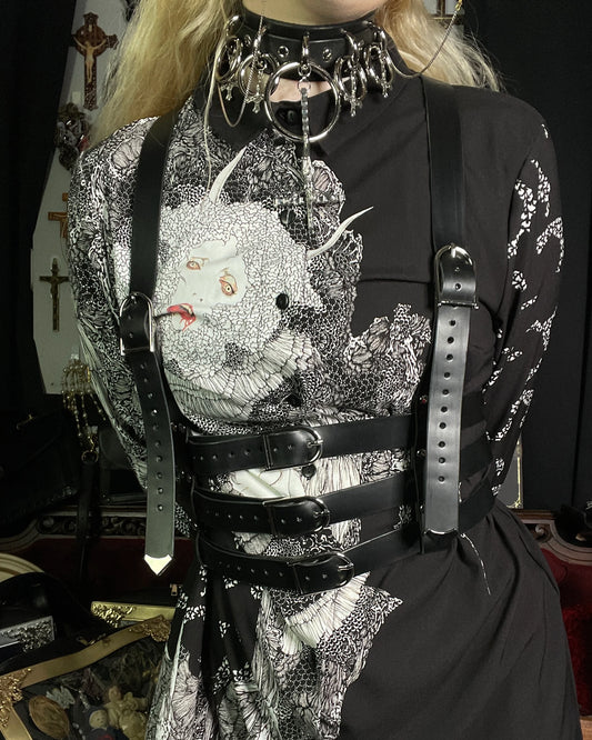 Person wearing a black and white patterned outfit with leather straps and a detailed collar