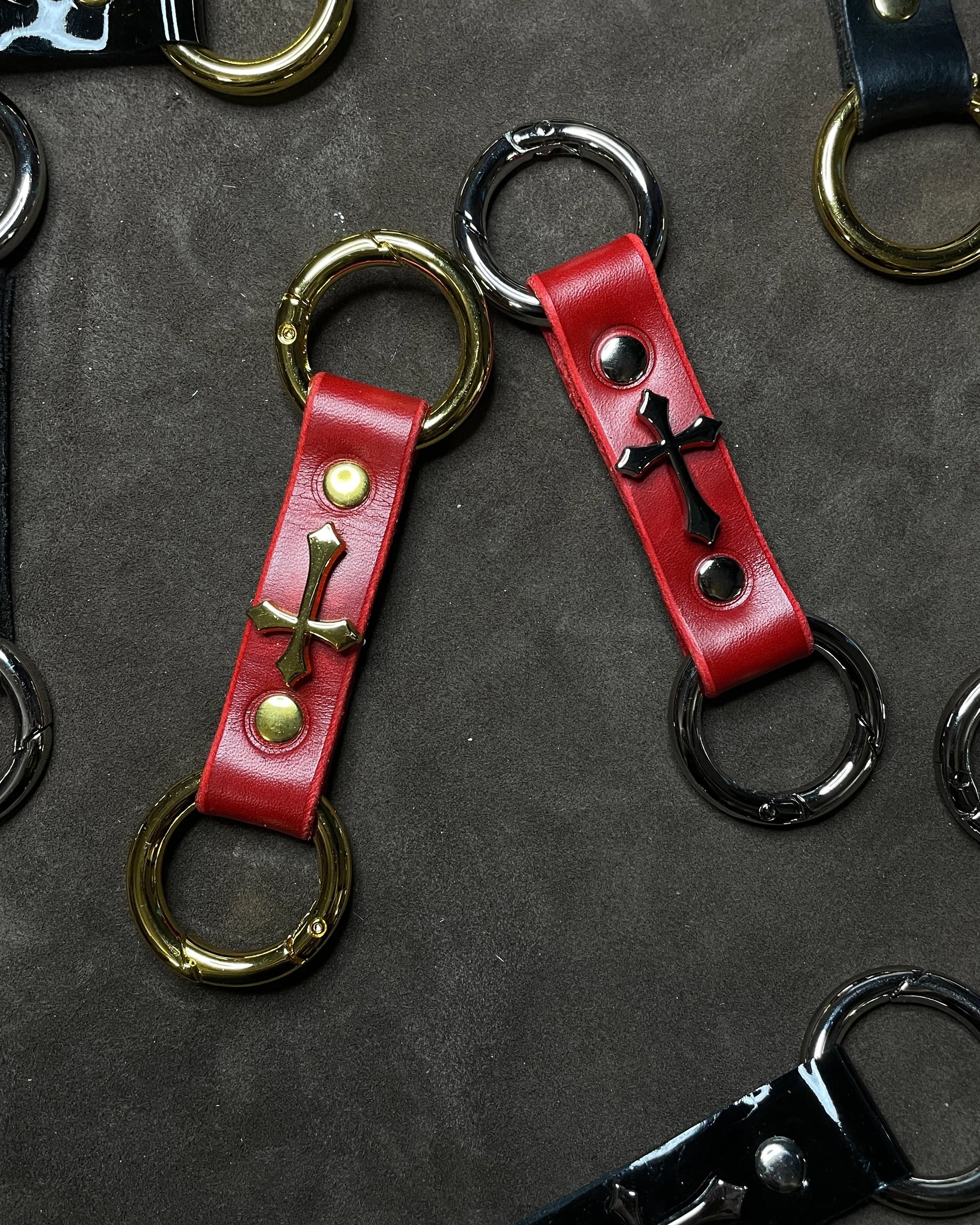 Red leather keychains with cross designs on a dark surface