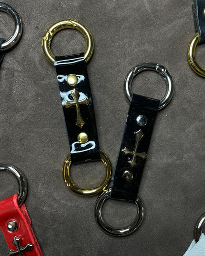 Collection of leather keychains with metal clasps on a gray surface