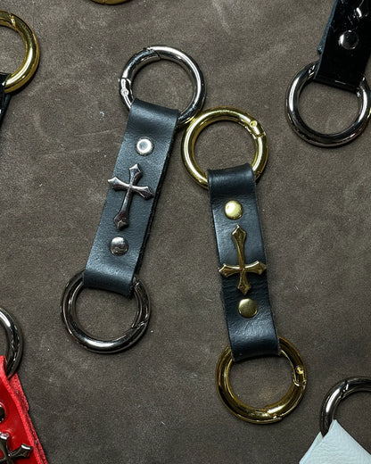 Leather keychains with metal rings and cross designs on a textured surface