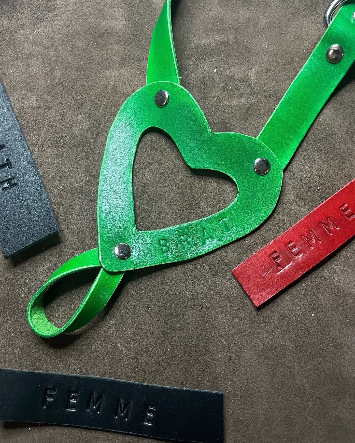 Green leather strap with heart-shaped cutout on a textured surface