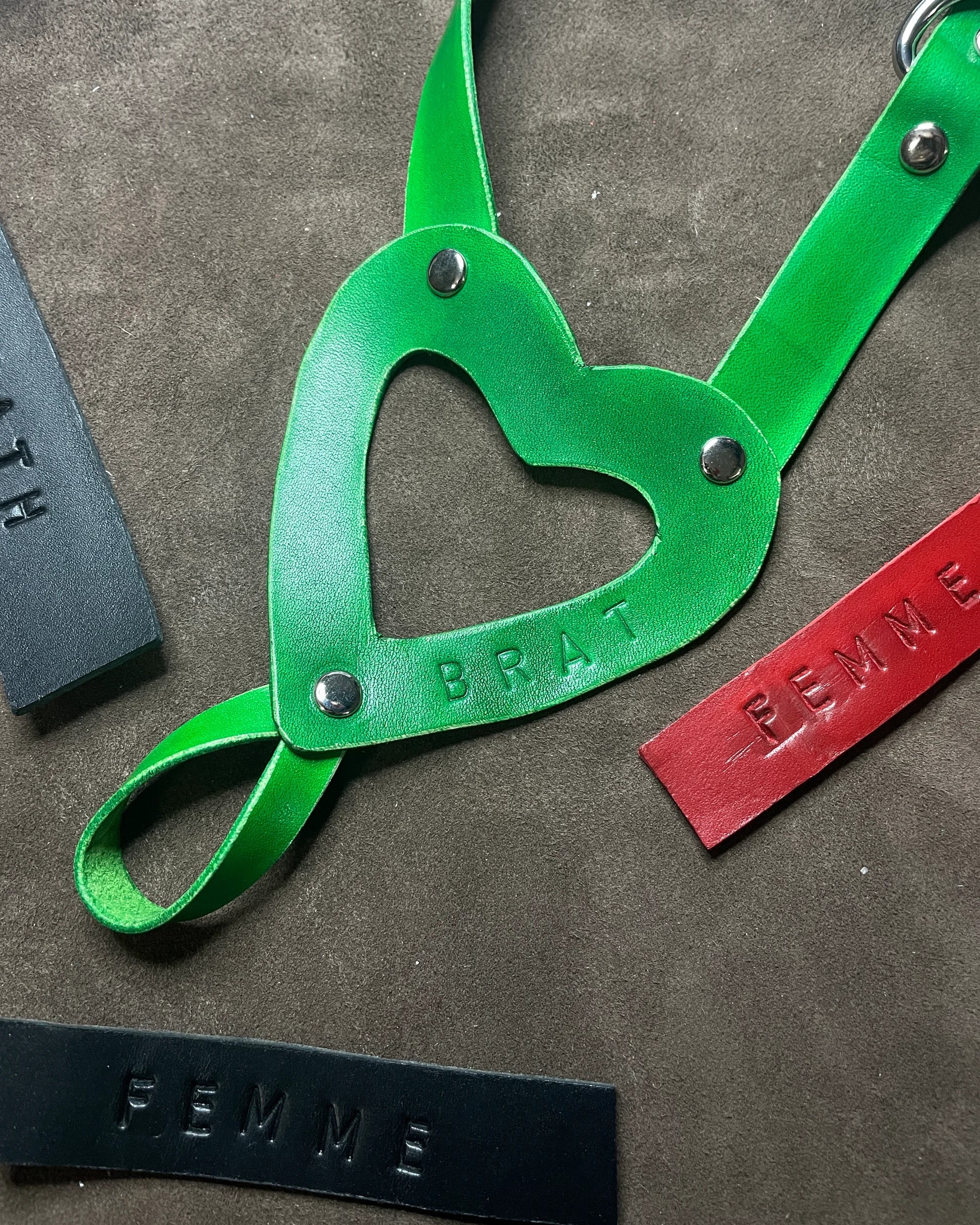 Green leather strap with heart-shaped cutout on a textured surface