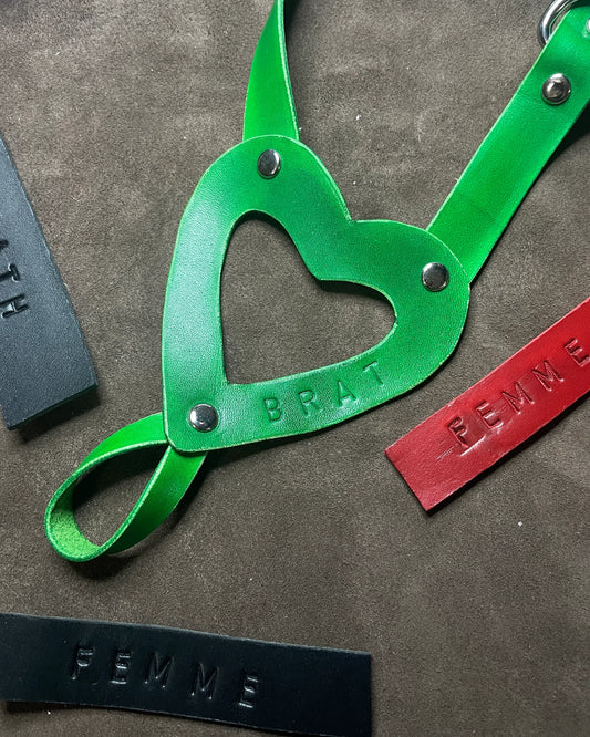 Green leather strap with heart-shaped cutout on a textured surface
