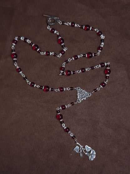 Necklace with red beads and silver clasp on a brown background