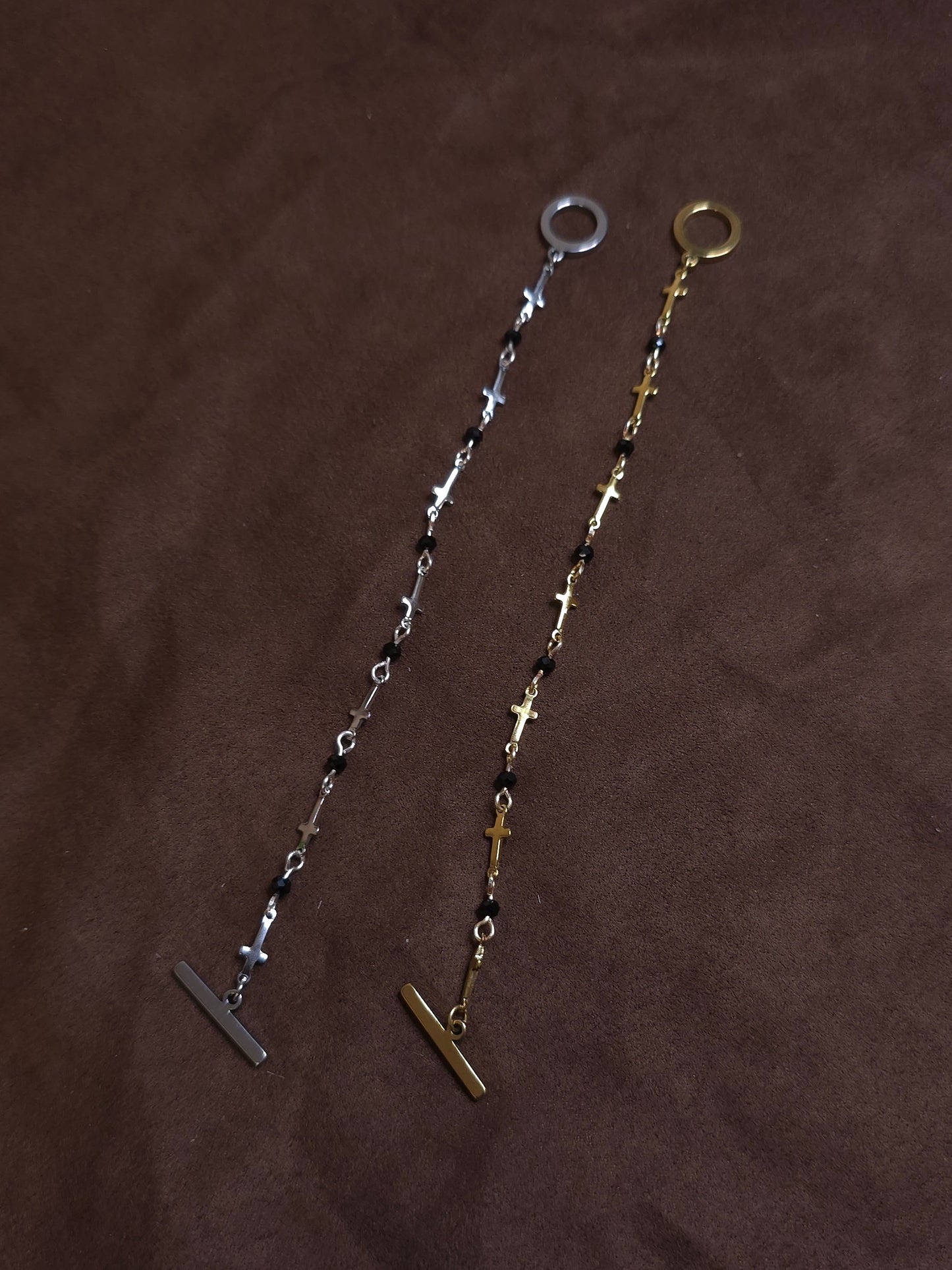 Two bracelets, one silver and one gold, on a brown fabric background