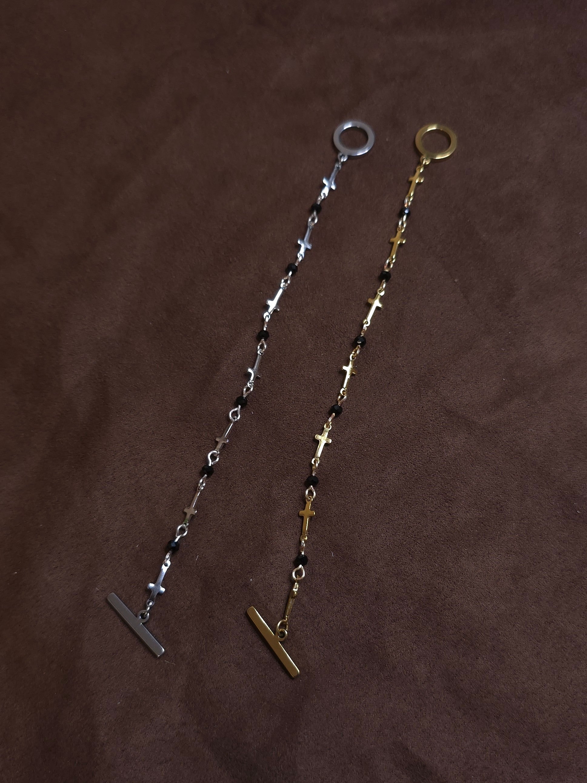 Two bracelets, one silver and one gold, on a brown fabric background