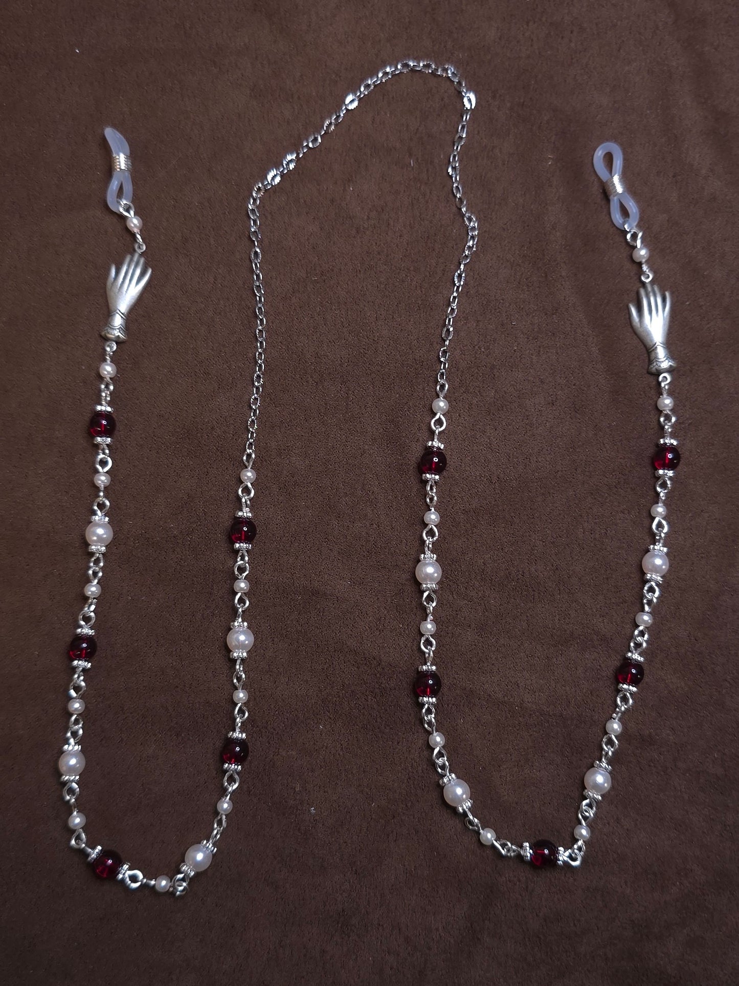 Silver chain with red and white beads on a brown background