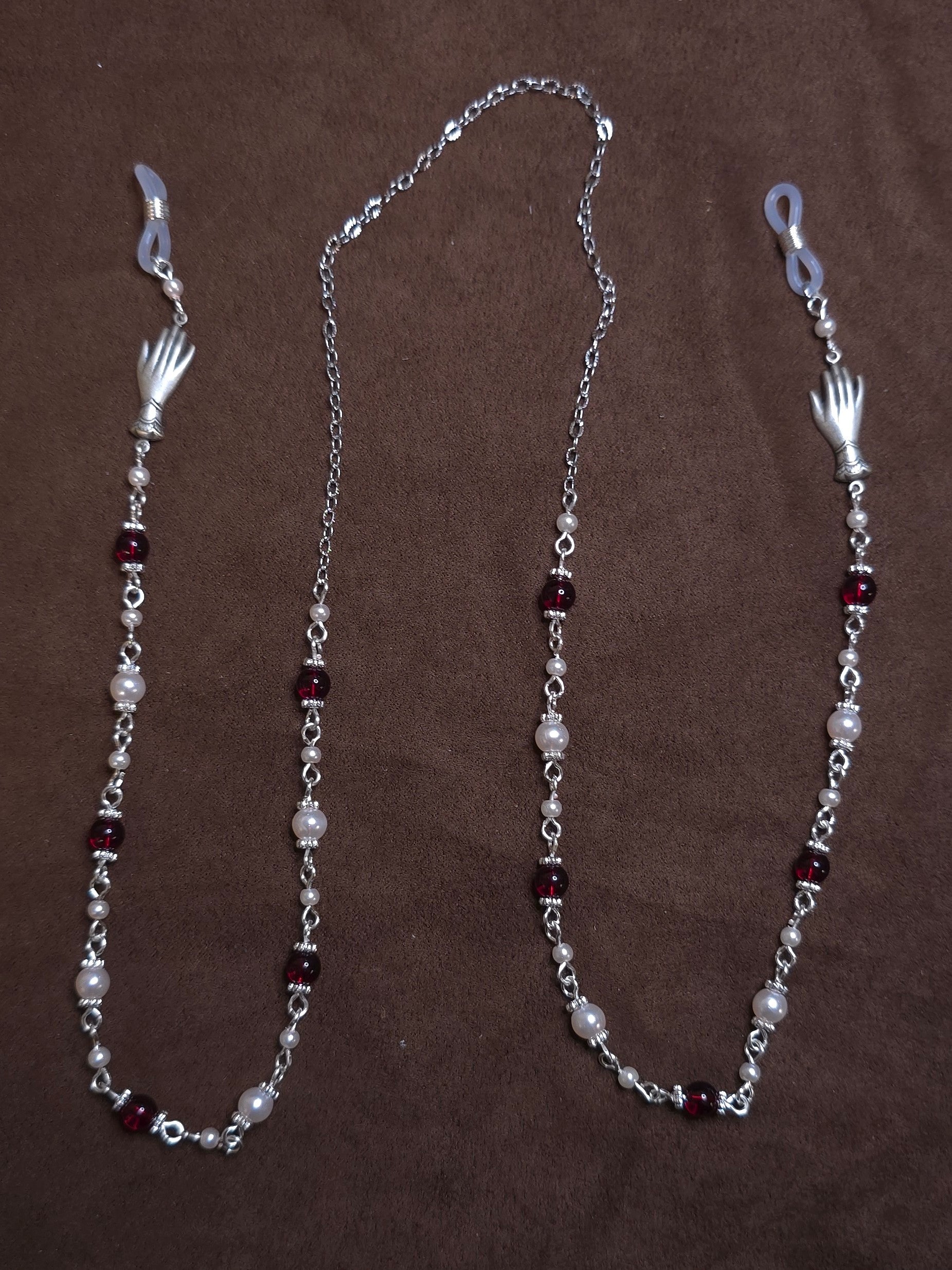 Silver chain with red and white beads on a brown background
