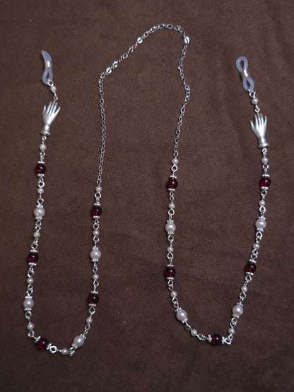 Silver chain with red and white beads on a brown background