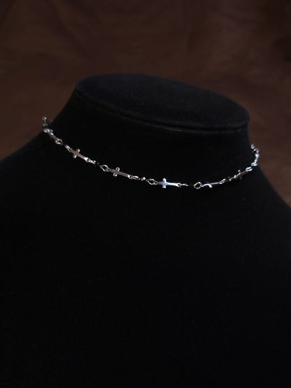 Silver chain necklace on a black mannequin bust against a dark background