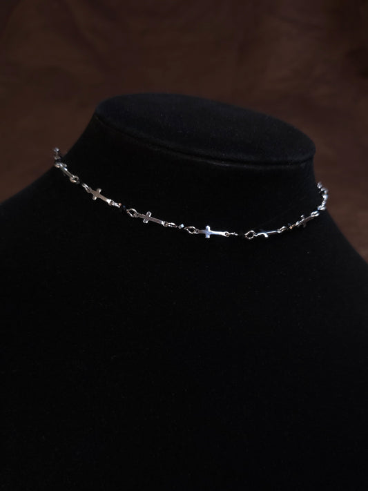 Silver chain necklace on a black mannequin bust against a dark background