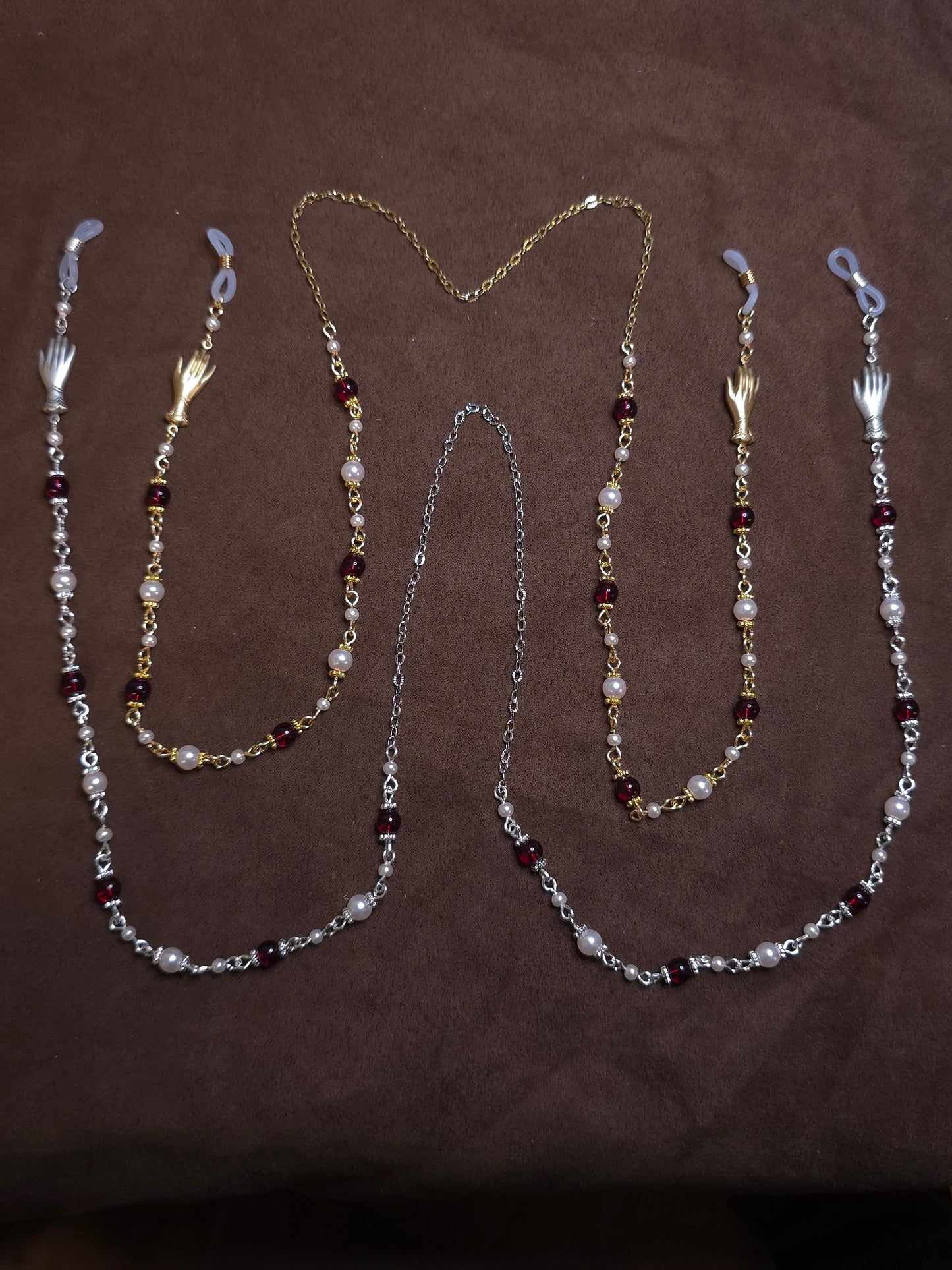 Two beaded glasses chains in silver and gold on brown background
