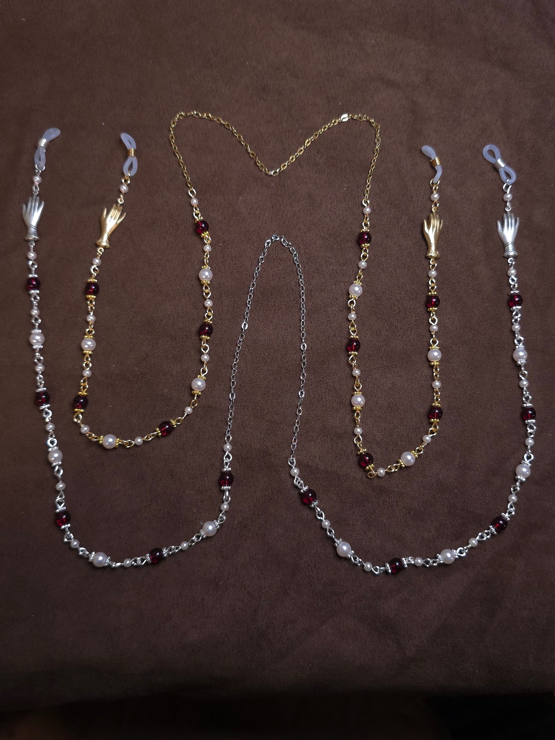Two beaded glasses chains in silver and gold on brown background