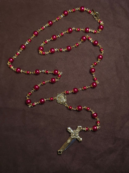 Red beaded rosary with a cross on a brown background