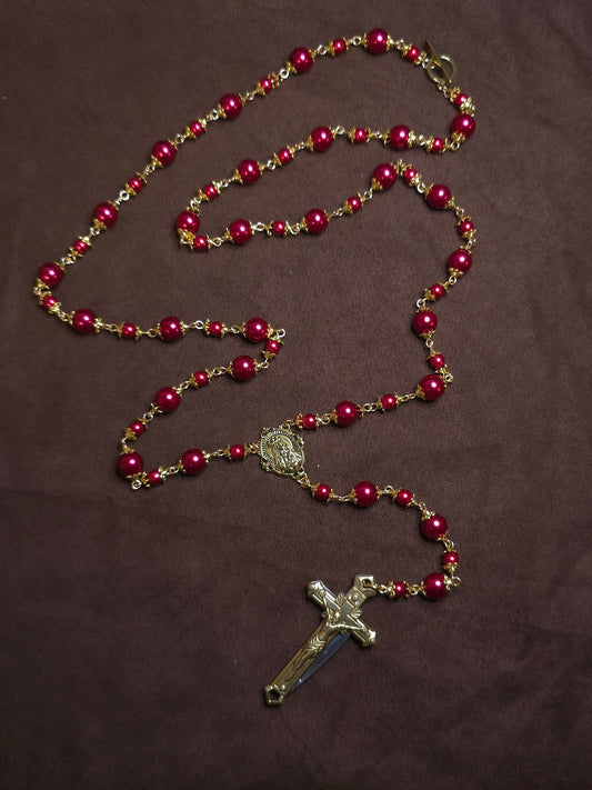 Red beaded rosary with a cross on a brown background