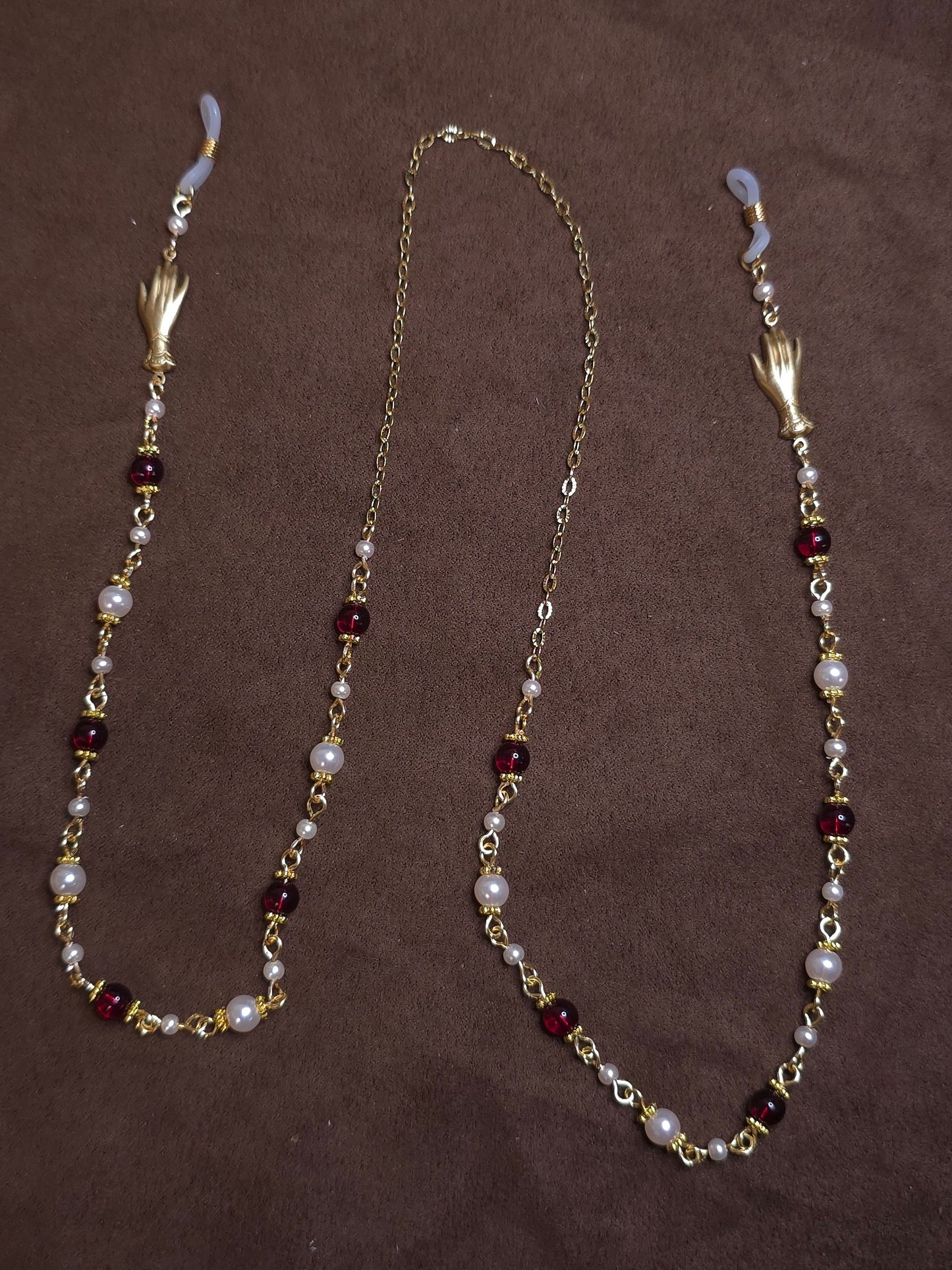 Glasses chain with pearls and red beads on a brown background