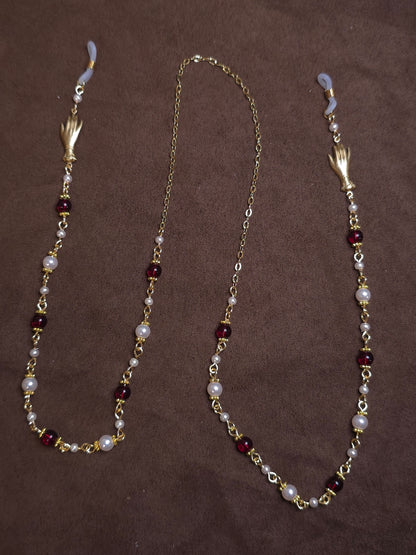 Glasses chain with pearls and red beads on a brown background